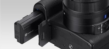 H&igrave;nh ảnh sản phẩm cho thấy nắp đậy ngăn chứa pin đang mở, với pin NP-FZ100 được lắp một phần
