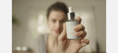 Hình ảnh người phụ nữ đang cầm và xem xét món đồ trang điểm trên tay