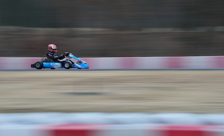 Hình ảnh mẫu về một cuộc đua xe go-kart ở tốc độ cao, được chụp với hiệu ứng làm mờ chuyển động ở hậu cảnh.