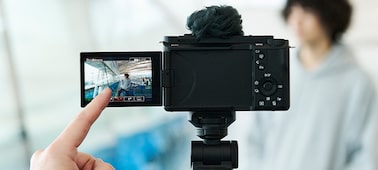 Hình ảnh ngón tay chạm vào màn hình cảm ứng của máy ảnh