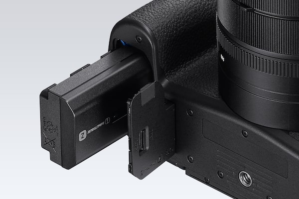 Hình ảnh sản phẩm cho thấy nắp đậy ngăn chứa pin đang mở, với pin NP-FZ100 được lắp một phần